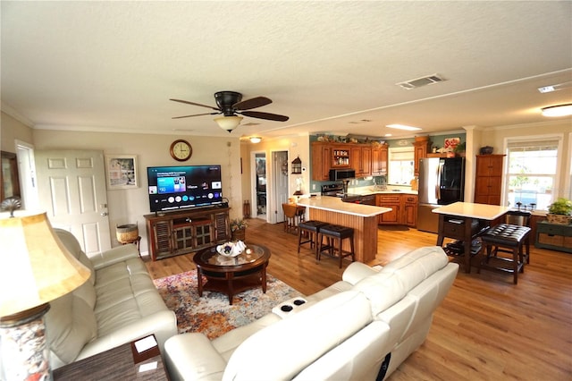 living room featuring ceiling fan, light hardwood / wood-style floors, and ornamental molding