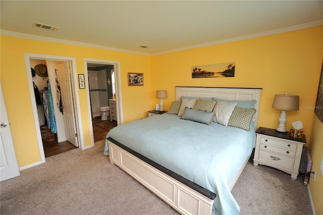 carpeted bedroom featuring ensuite bath and ornamental molding