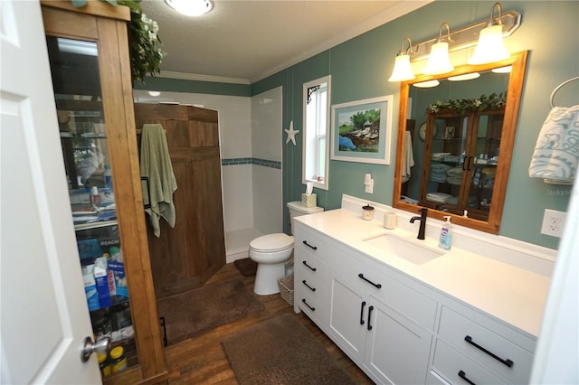 bathroom featuring vanity, a shower, hardwood / wood-style flooring, toilet, and ornamental molding