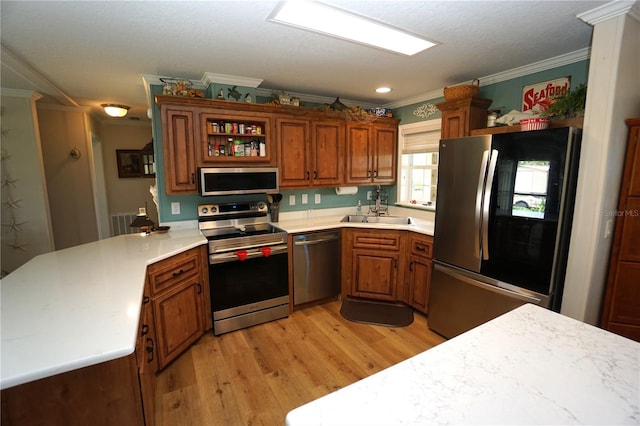 kitchen with sink, stainless steel appliances, kitchen peninsula, light hardwood / wood-style floors, and ornamental molding