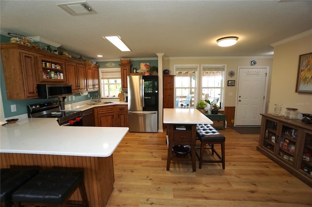 kitchen featuring kitchen peninsula, a kitchen breakfast bar, stainless steel appliances, sink, and light hardwood / wood-style flooring