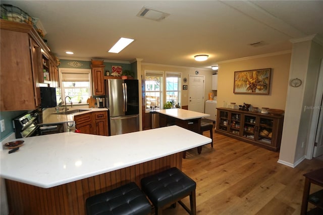 kitchen featuring a kitchen breakfast bar, sink, light hardwood / wood-style floors, kitchen peninsula, and stainless steel appliances