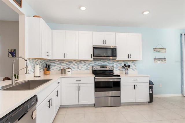 kitchen featuring sink, decorative backsplash, appliances with stainless steel finishes, light tile patterned flooring, and white cabinetry