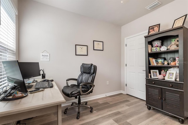 office area with light hardwood / wood-style flooring and a healthy amount of sunlight