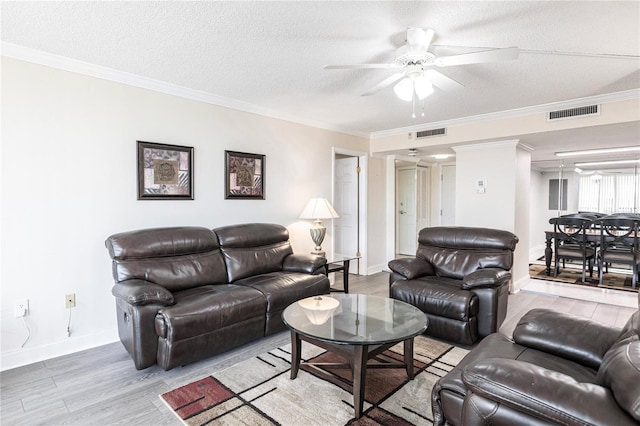 living room featuring ceiling fan, wood-type flooring, a textured ceiling, and ornamental molding