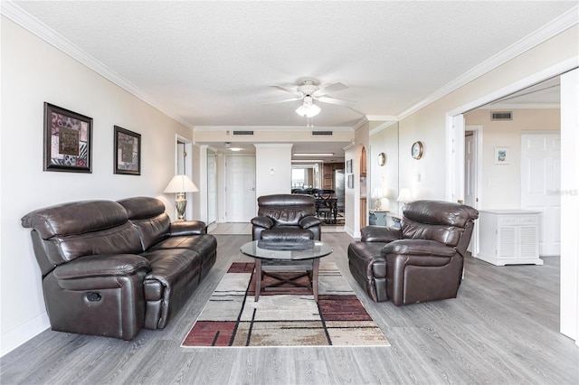 living room featuring ceiling fan, a textured ceiling, light hardwood / wood-style flooring, and ornamental molding