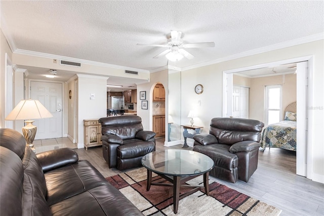 living room featuring ceiling fan, a textured ceiling, light hardwood / wood-style flooring, and ornamental molding