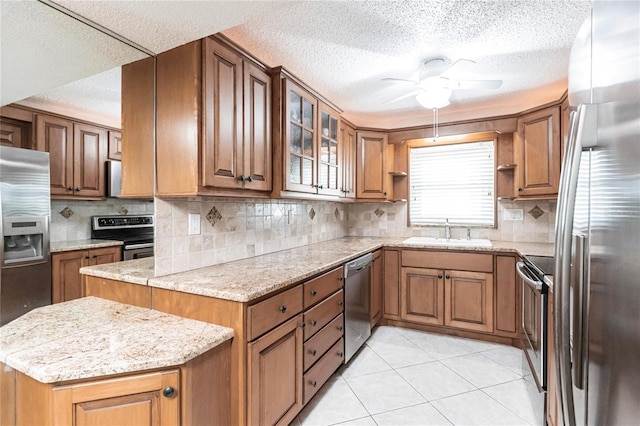 kitchen with ceiling fan, tasteful backsplash, light stone counters, sink, and stainless steel appliances