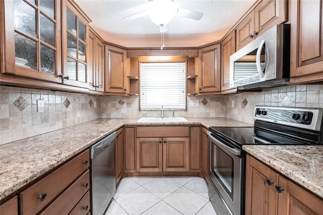 kitchen with appliances with stainless steel finishes, ceiling fan, light tile patterned floors, and tasteful backsplash