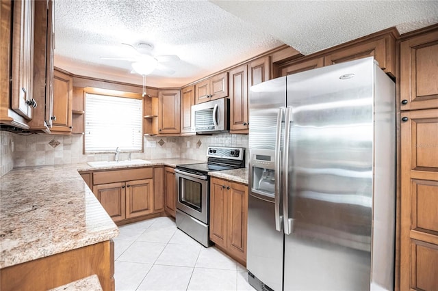 kitchen with sink, light tile patterned floors, decorative backsplash, ceiling fan, and stainless steel appliances