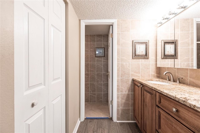 bathroom with tile walls, a textured ceiling, vanity, and hardwood / wood-style floors