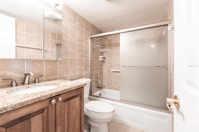 full bathroom featuring tile walls, a textured ceiling, vanity, shower / bath combination with glass door, and toilet