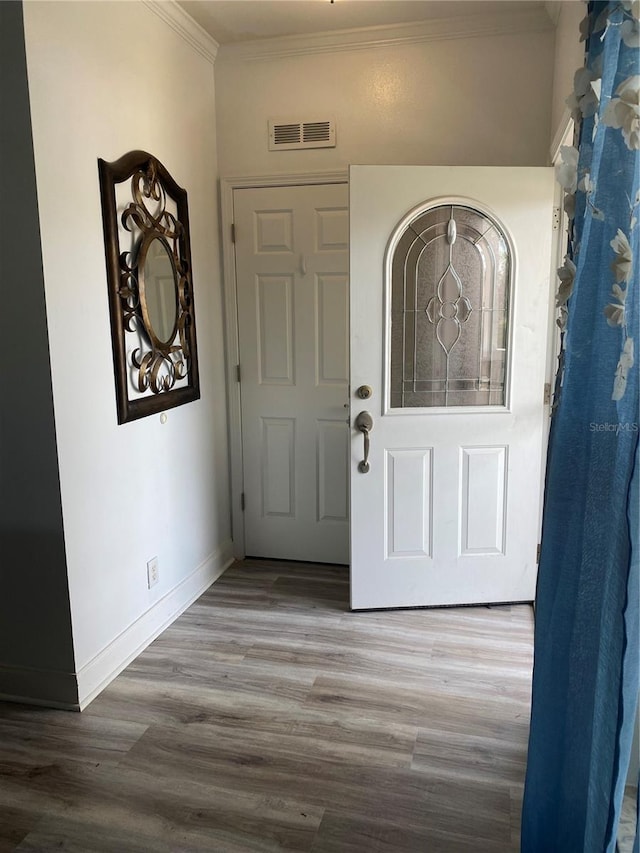 foyer entrance featuring ornamental molding, baseboards, visible vents, and wood finished floors