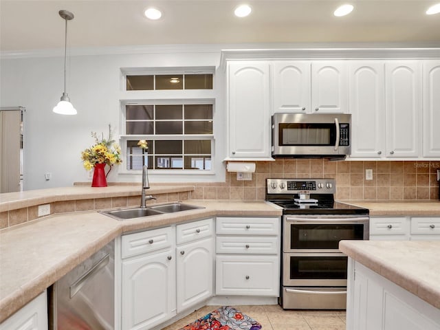 kitchen featuring a sink, pendant lighting, crown molding, appliances with stainless steel finishes, and tasteful backsplash