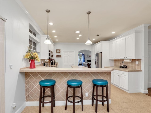 kitchen featuring stainless steel appliances, a kitchen bar, arched walkways, and recessed lighting