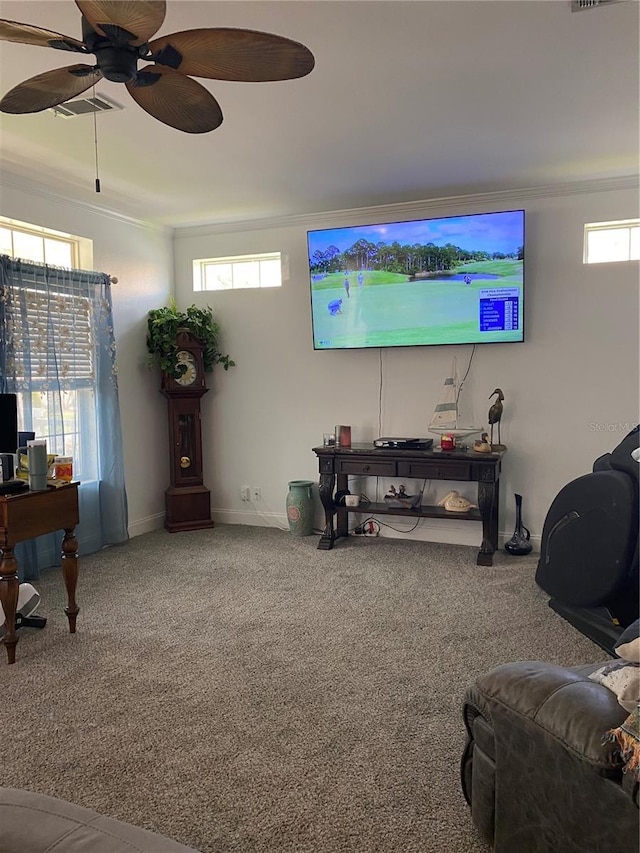 living area featuring crown molding, a healthy amount of sunlight, a ceiling fan, and carpet