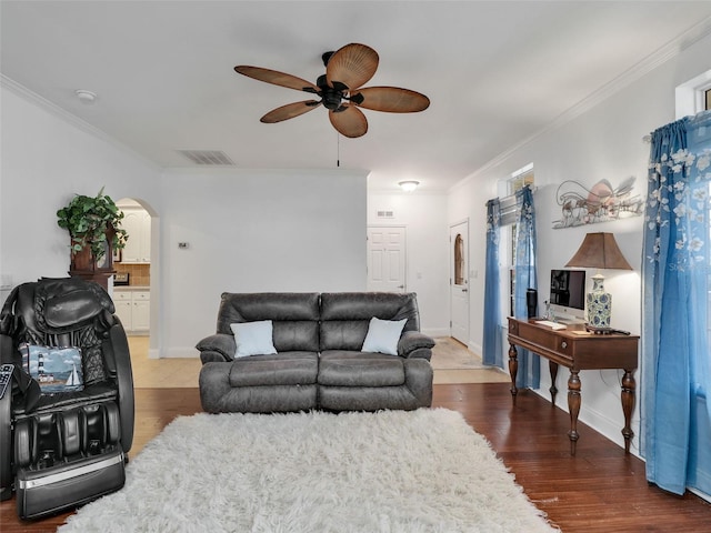 living room featuring crown molding, arched walkways, a ceiling fan, and wood finished floors