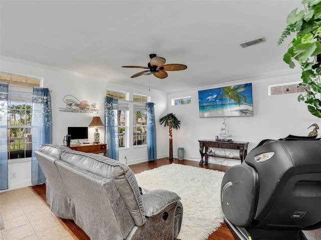living area with visible vents, wood finished floors, a ceiling fan, and ornamental molding