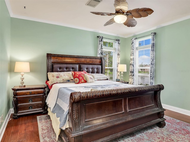 bedroom featuring wood finished floors, visible vents, baseboards, and ornamental molding
