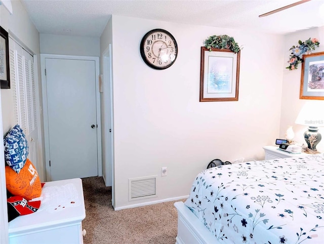 carpeted bedroom with a textured ceiling, ceiling fan, and a closet