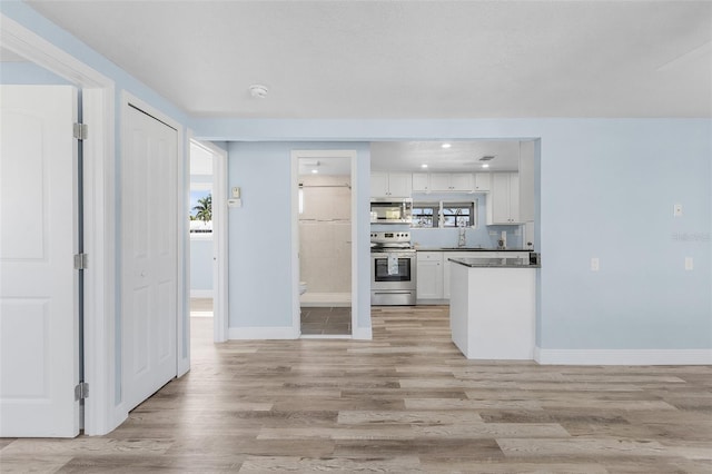 kitchen featuring stainless steel appliances, sink, white cabinets, and light wood-type flooring