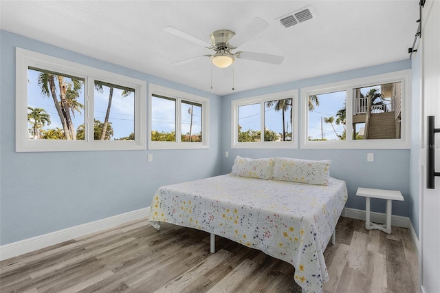 bedroom with multiple windows, ceiling fan, and light hardwood / wood-style floors