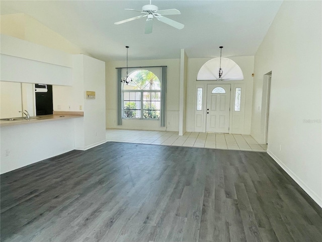 foyer with ceiling fan with notable chandelier, hardwood / wood-style flooring, lofted ceiling, and sink