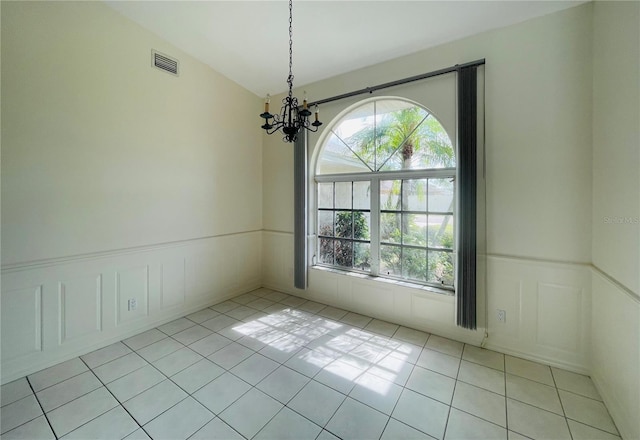 unfurnished room featuring a chandelier, light tile patterned floors, and a healthy amount of sunlight