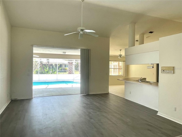 unfurnished living room featuring dark hardwood / wood-style floors, ceiling fan, and lofted ceiling