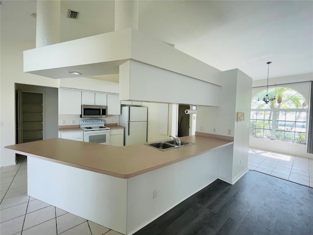 kitchen with white appliances, sink, decorative light fixtures, a notable chandelier, and white cabinetry