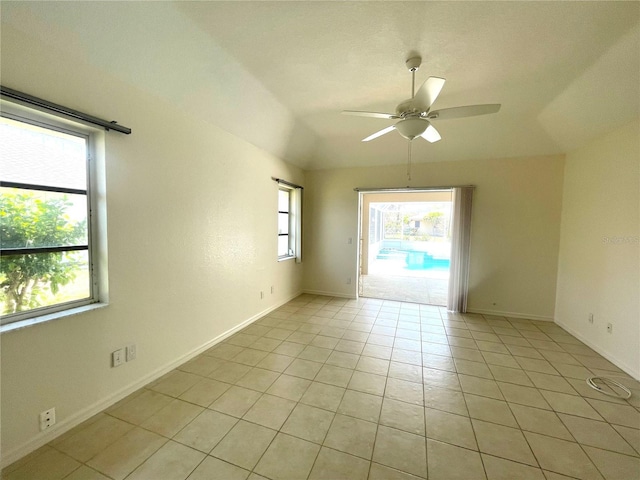 empty room with ceiling fan, lofted ceiling, and light tile patterned flooring