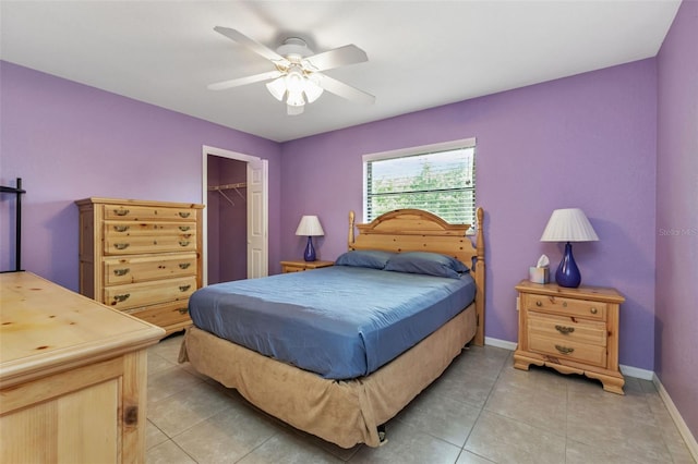 bedroom featuring ceiling fan, light tile patterned floors, a closet, and a walk in closet