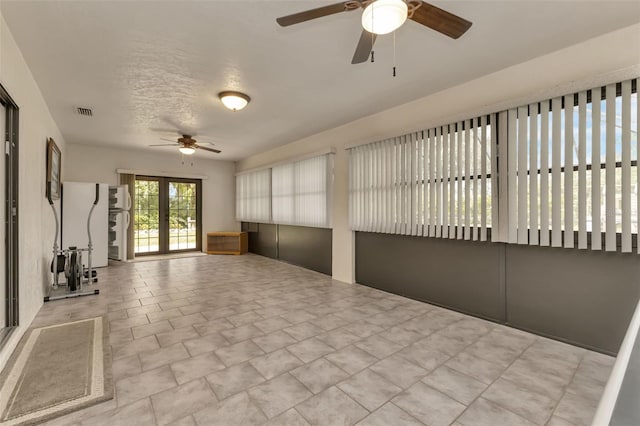 unfurnished sunroom with ceiling fan and french doors