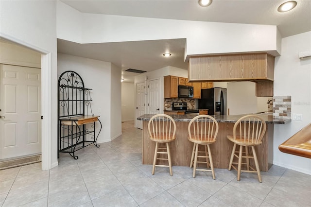 kitchen featuring a kitchen bar, stainless steel appliances, decorative backsplash, sink, and kitchen peninsula