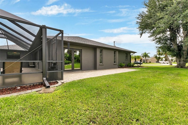 exterior space featuring glass enclosure, a patio, and a yard