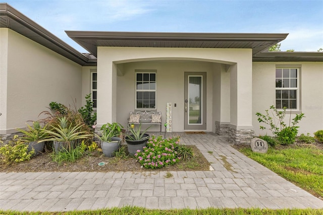 property entrance with a porch, stone siding, and stucco siding