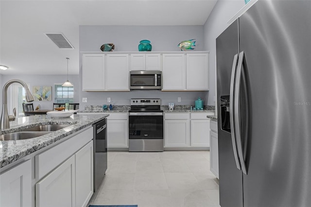 kitchen featuring white cabinetry, light tile patterned floors, stainless steel appliances, light stone countertops, and sink