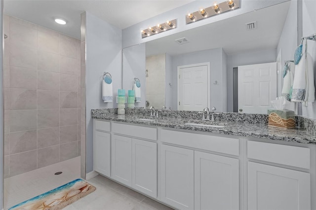 bathroom with a tile shower, tile patterned floors, and dual bowl vanity