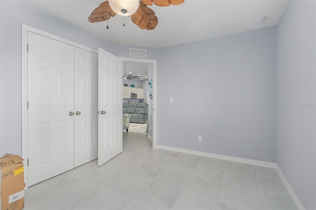 unfurnished bedroom with light tile patterned floors, a closet, and ceiling fan