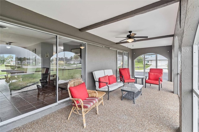 sunroom with ceiling fan and beamed ceiling