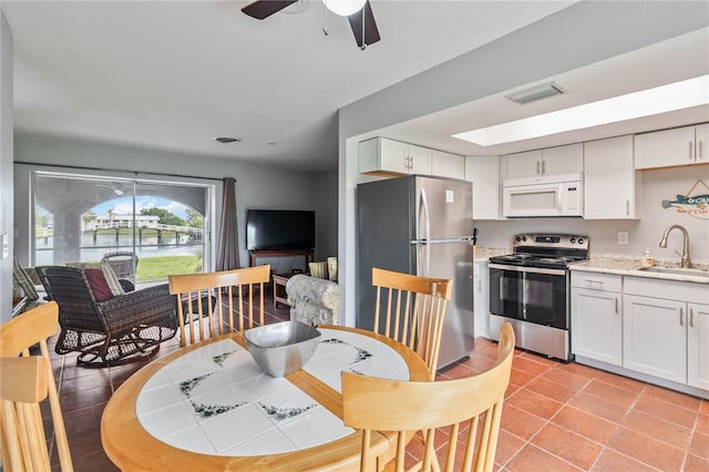 kitchen featuring ceiling fan, sink, light tile patterned floors, stainless steel appliances, and white cabinets