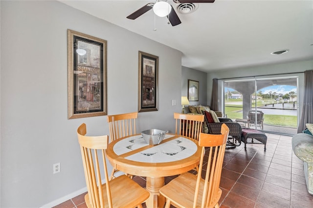 dining room with ceiling fan and dark tile patterned flooring