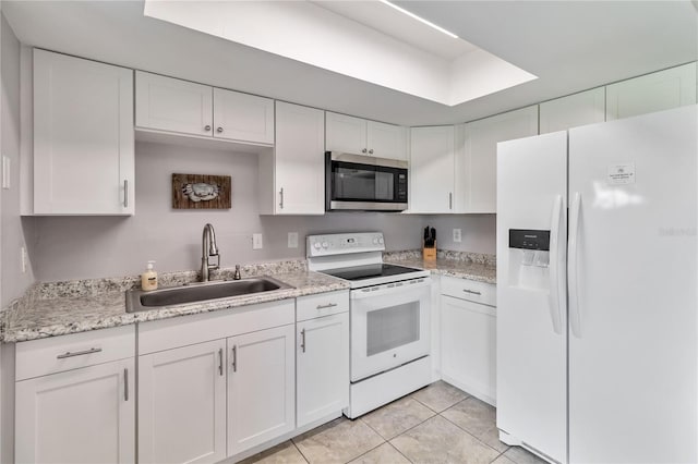 kitchen with light tile patterned floors, white cabinetry, white appliances, light stone countertops, and sink