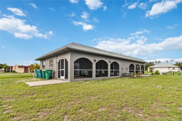 rear view of house featuring central AC unit, a yard, and a sunroom