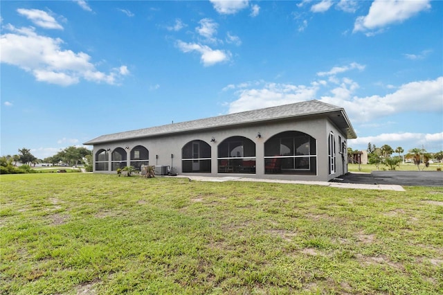 rear view of property featuring cooling unit and a lawn