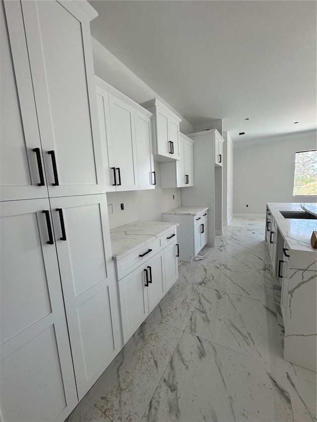 kitchen featuring light stone countertops and white cabinetry