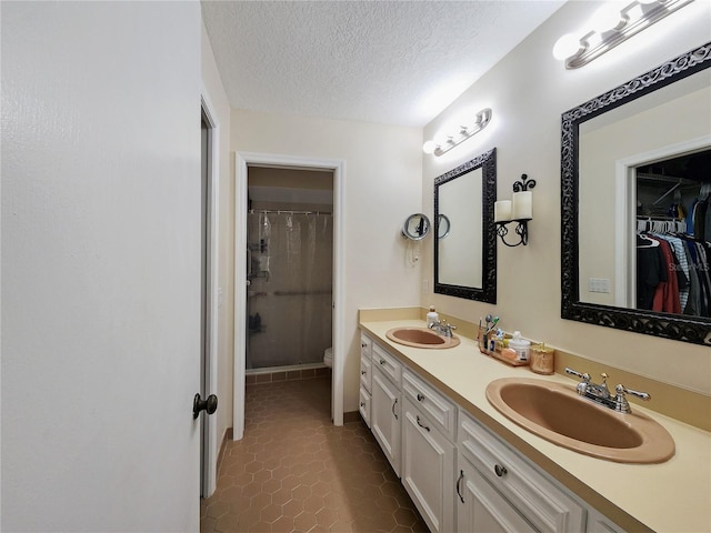 bathroom with a textured ceiling, toilet, dual vanity, tile patterned floors, and curtained shower