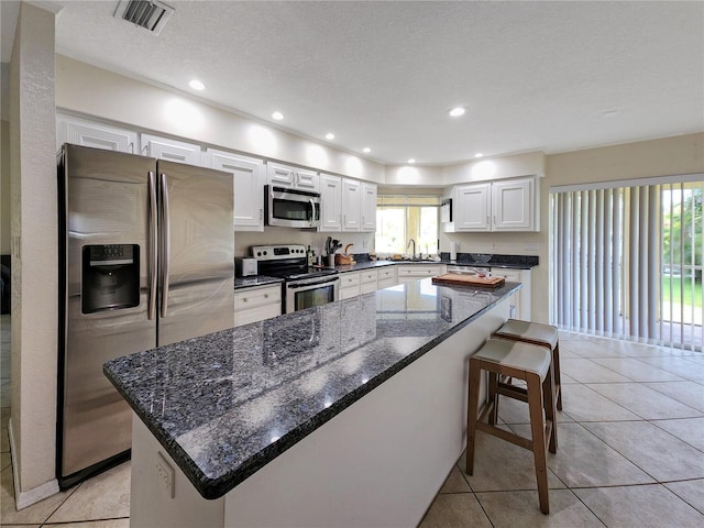 695 Coronado Dr, Punta Gorda, FL 33950 - kitchen featuring visible vents, dark stone counters, stainless steel appliances, white cabinets, and a kitchen bar