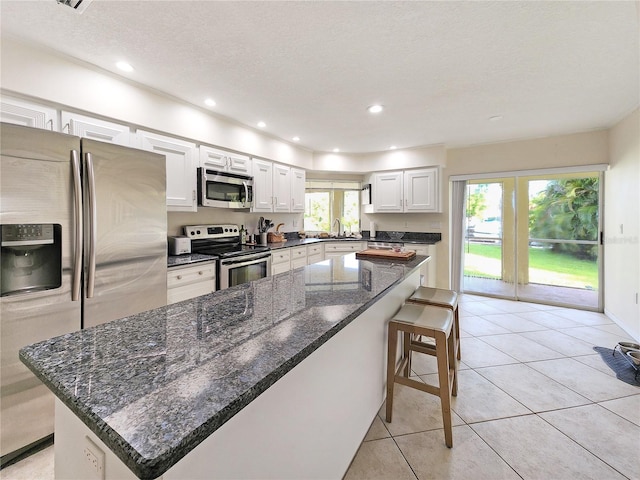 kitchen featuring white cabinetry, a center island, plenty of natural light, and stainless steel appliances