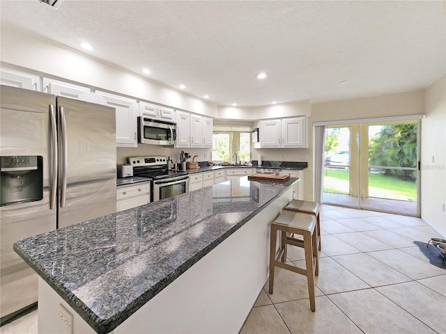 695 Coronado Dr, Punta Gorda, FL 33950 - kitchen with a kitchen breakfast bar, a center island, white cabinetry, stainless steel appliances, and light tile patterned flooring